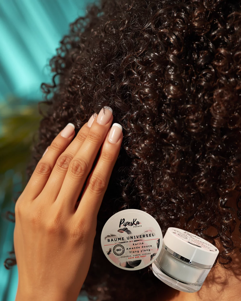 Femme aux cheveux texturés appliquant le Baume Universel Pipeska pour définir les boucles et sceller l'hydratation. Baume Universel Bio & 100% Naturel | Soin Visage, Corps, Cheveux | Pipeska